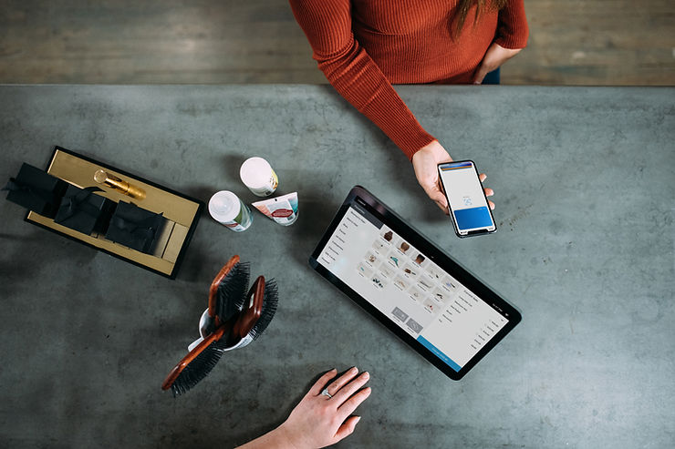 Various objects situated in between a customer and employee who works on a tablet device.